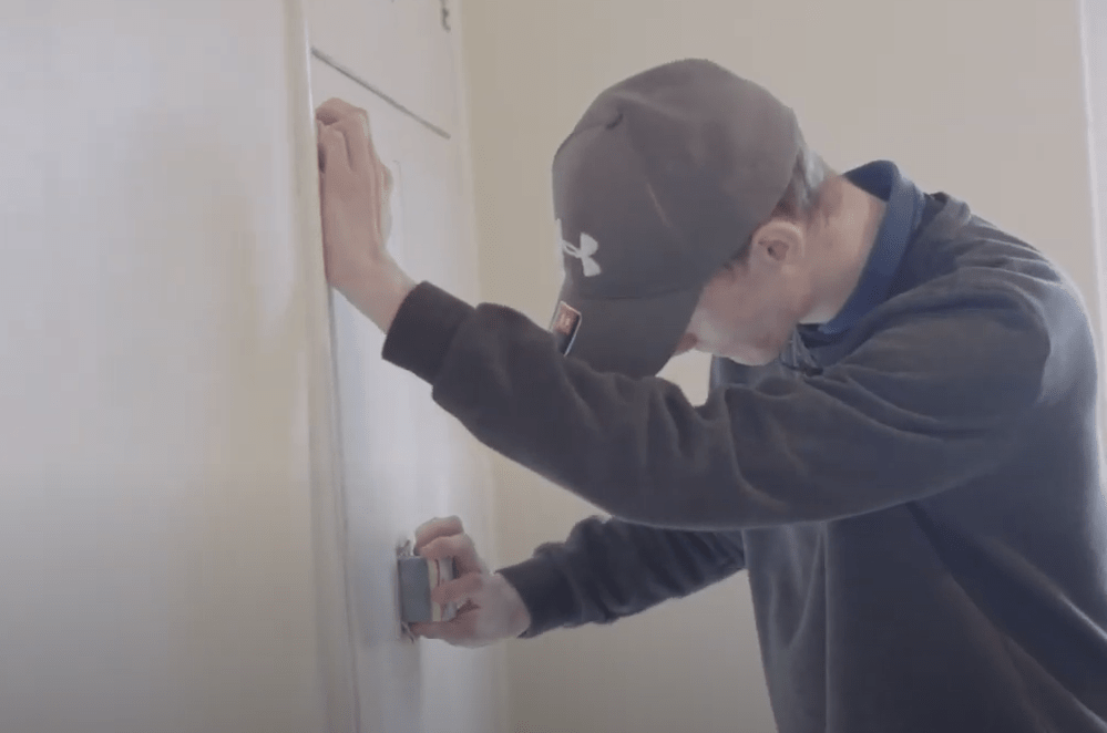 person sanding a wall